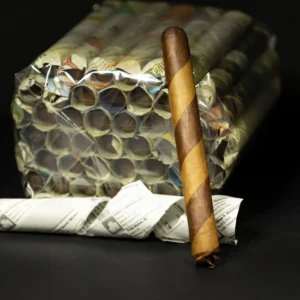 A cigar leaning against a large bundle of rolled newspapers wrapped in clear plastic on a dark surface.
