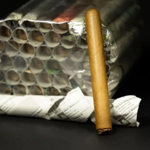 Bundle of cigarettes wrapped in plastic with a single brown cigar standing upright beside it.