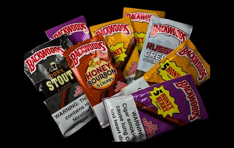 Assorted Backwoods cigar packaging in various flavors laid out on a black background.