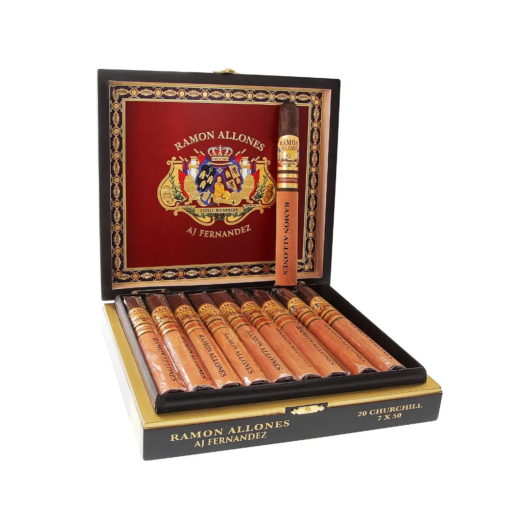 Open luxury cigar box revealed with 20 Ramon Allones AJ Fernandez cigars aligned inside; ornate crest on red interior lid edge suggests premium brand.